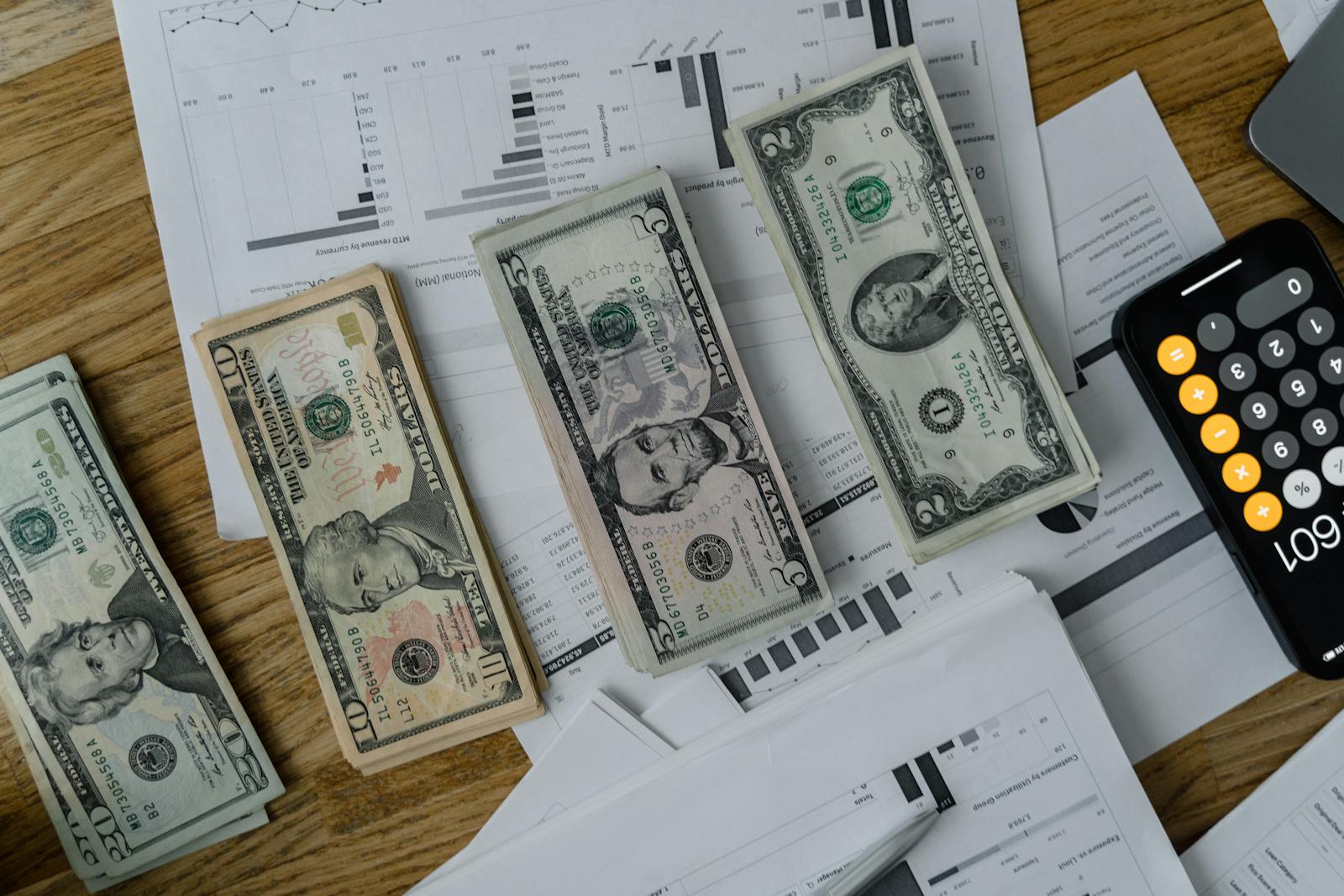 Un espace de travail aménagé avec de l'argent liquide, des documents et une calculatrice symbolisant l'analyse financière et la budgétisation.