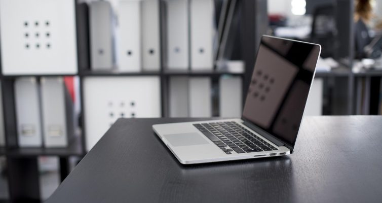 Ordinateur portable ouvert sur un bureau dans un espace de travail professionnel avec étagères