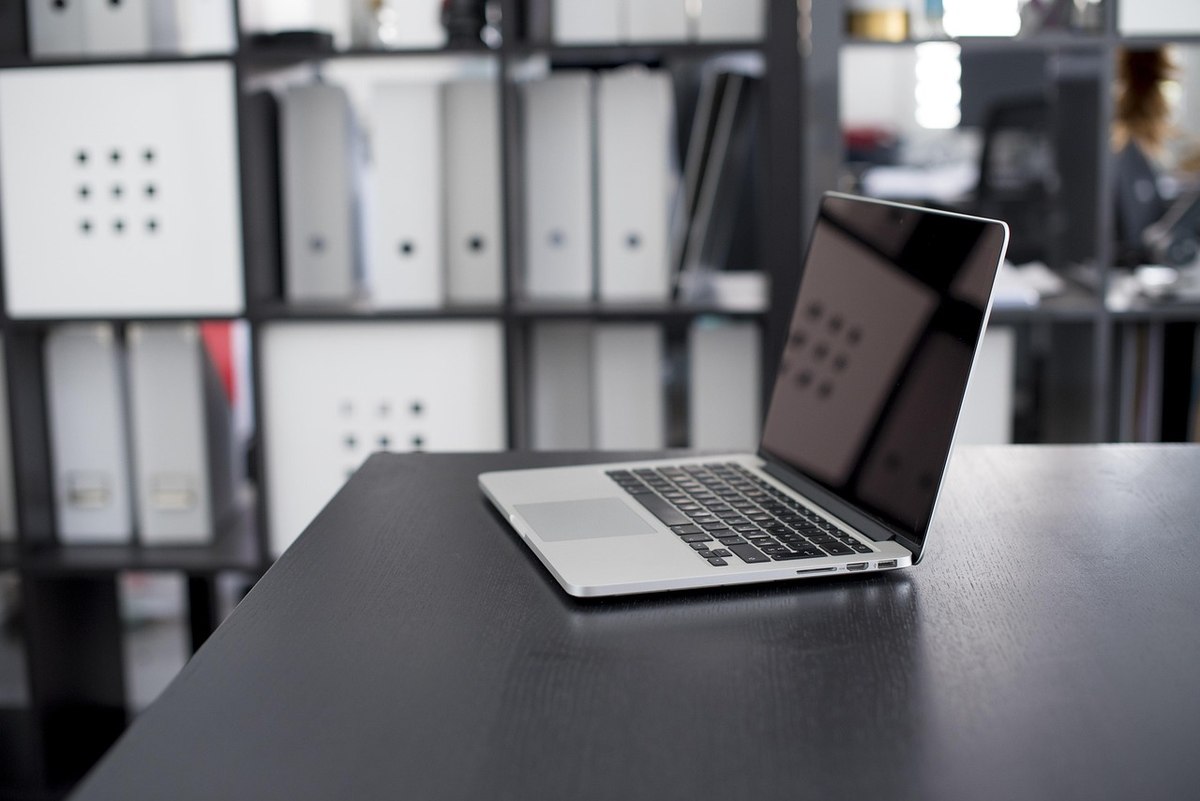 Ordinateur portable ouvert sur un bureau dans un espace de travail professionnel avec étagères