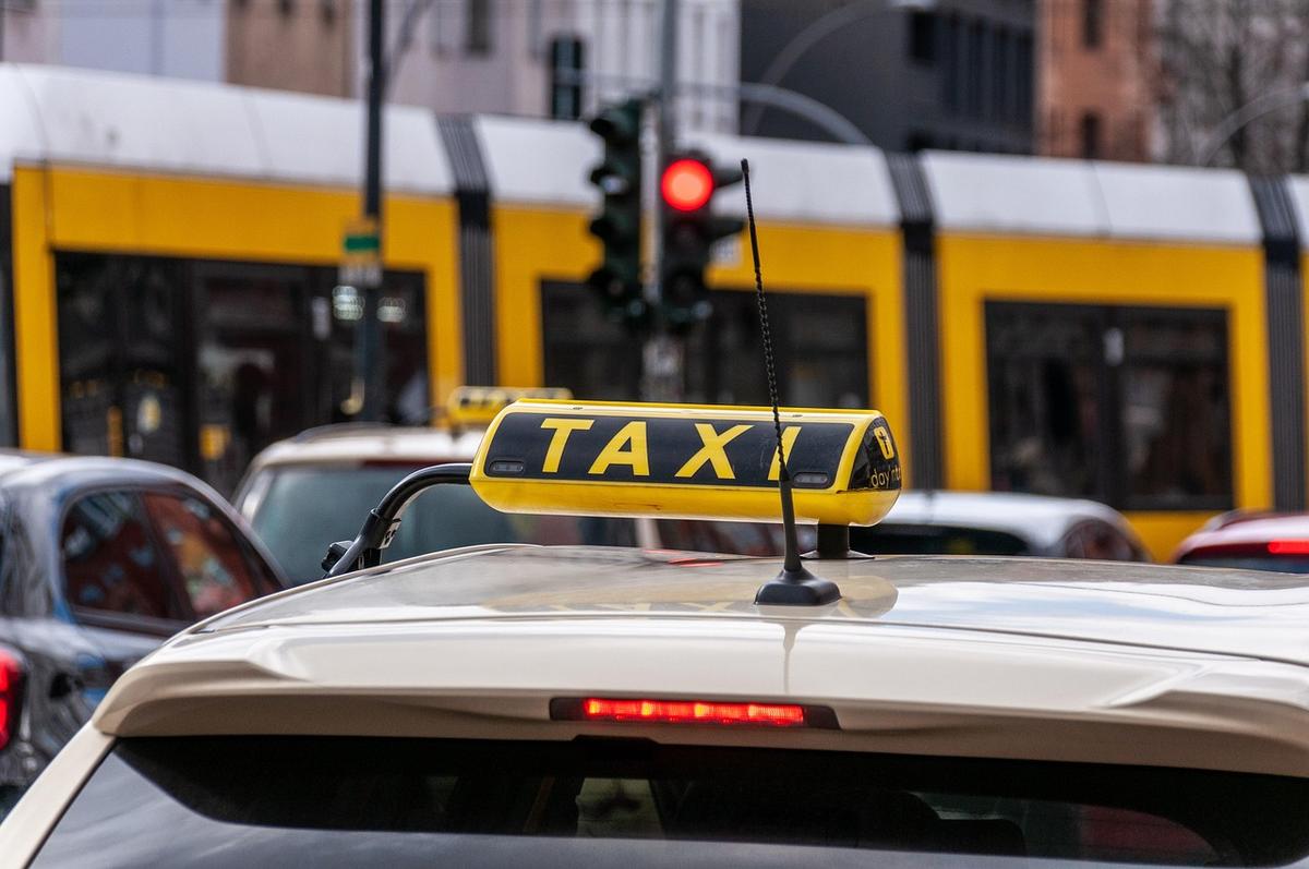 Taxi dans la rue, devant un tramway, avec d'autres voitures