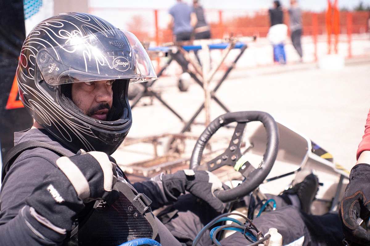 Un homme en tenue de karting tient un volant de karting