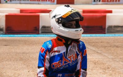 Un coureur en combinaison bleue et casque blanc sur piste terre