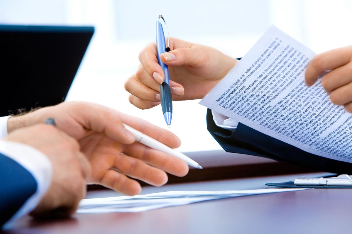 Des mains tiennent stylos et feuille de papier sur table