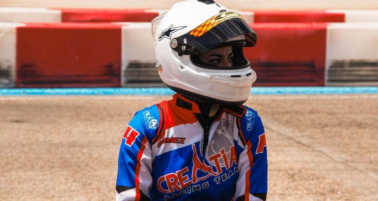 Un coureur en karting portant un casque blanc et une combinaison bleue