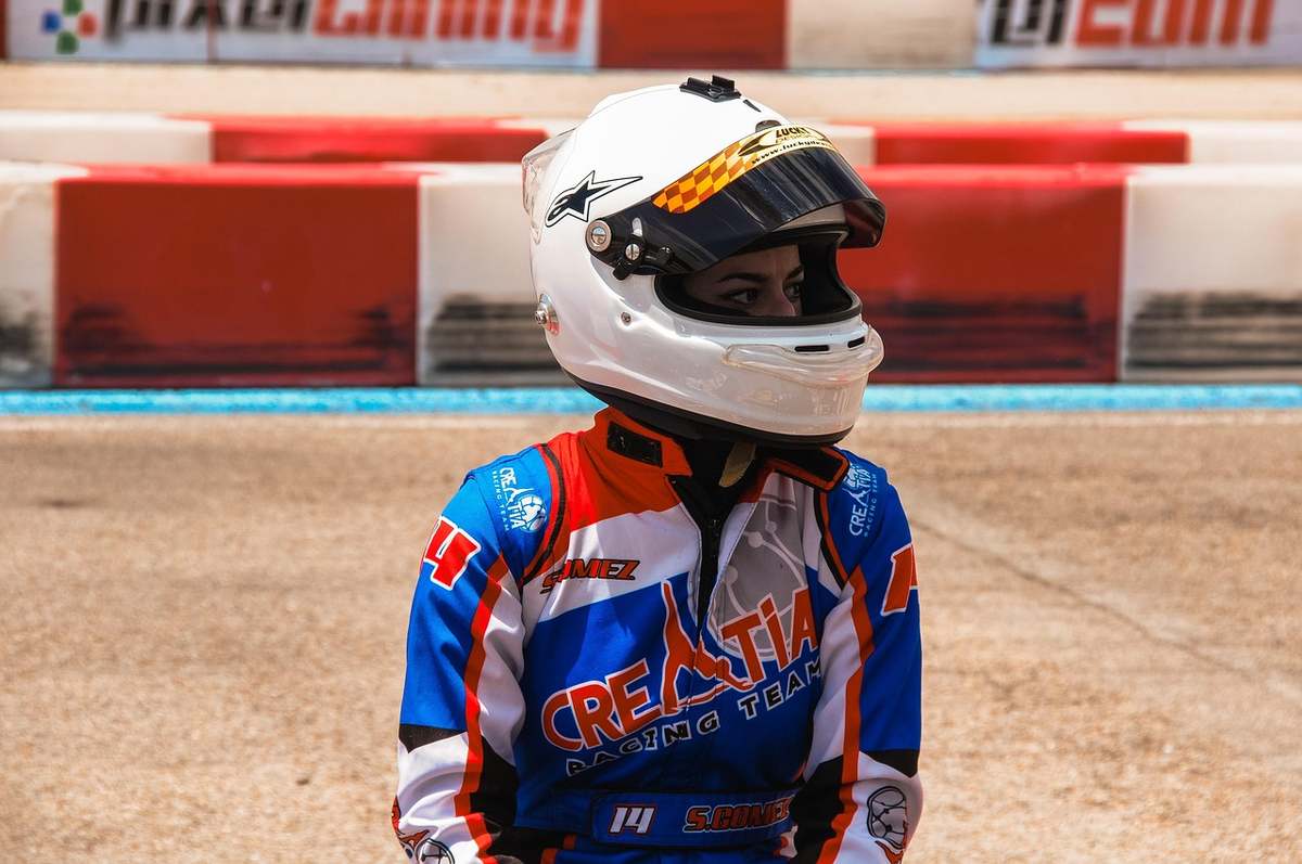 Un coureur en karting portant un casque blanc et une combinaison bleue